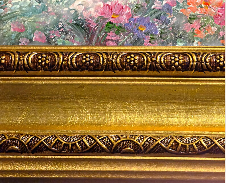 May include: Close-up of a framed floral painting. The frame is gold with intricate, dark brown decorative elements. The painting features a colorful array of pink, purple, and orange flowers.