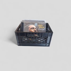 May include: A black plastic milk crate filled with vinyl records. The top record features the album cover for "What's Going On" by Marvin Gaye. The crate has a diamond pattern design.