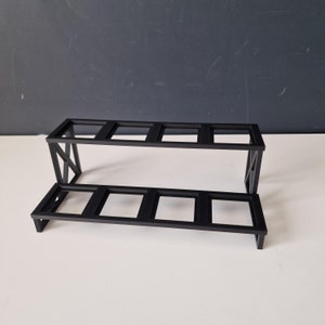 Puede incluir: Una estanter&iacute;a de metal negro con dos niveles y seis aberturas rectangulares. La estanter&iacute;a est&aacute; hecha de metal resistente y tiene un dise&ntilde;o simple y moderno.