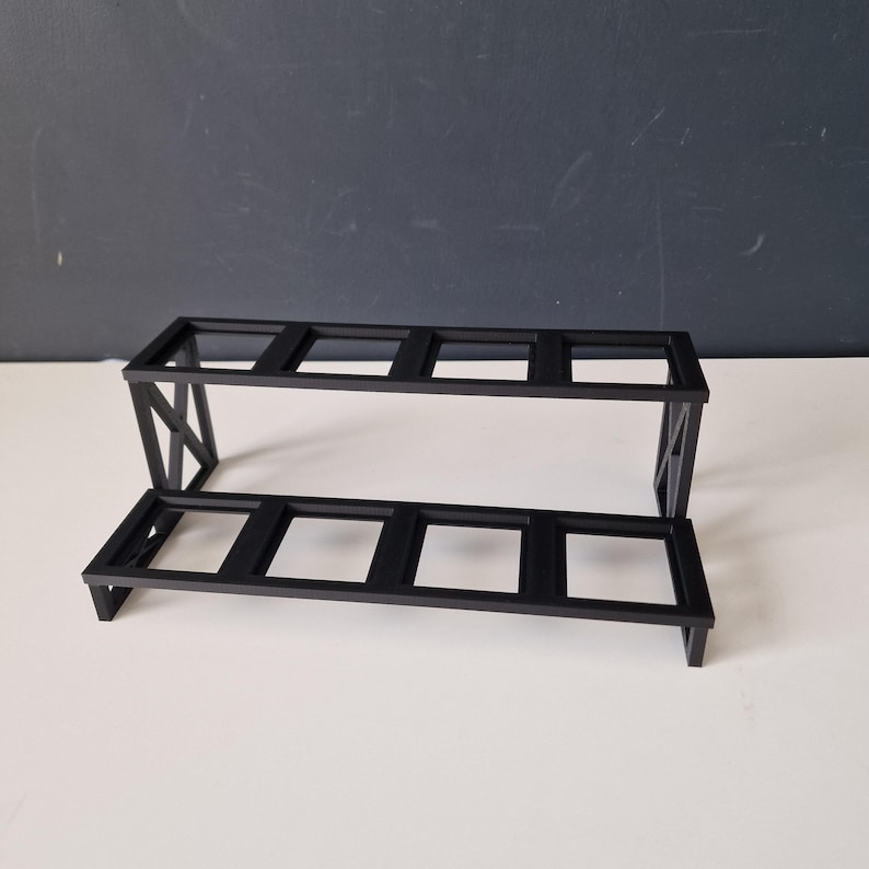 Puede incluir: Una estanter&iacute;a de metal negro con dos niveles y seis aberturas rectangulares. La estanter&iacute;a est&aacute; hecha de metal resistente y tiene un dise&ntilde;o simple y moderno.