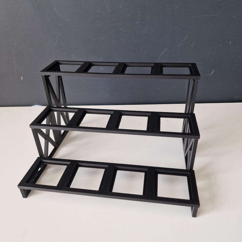 Puede incluir: Una estanter&iacute;a de metal negro de tres niveles con seis aberturas rectangulares en cada nivel. La estanter&iacute;a est&aacute; hecha de metal negro resistente y tiene un dise&ntilde;o moderno y minimalista.