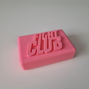 May include: A pink rectangular bar of soap with the words "FIGHT CLUB" embossed on the top.