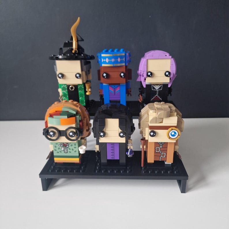Puede incluir: Un conjunto de seis minifiguras, cada una con un dise&ntilde;o y una combinaci&oacute;n de colores &uacute;nicos. Las minifiguras se muestran en un soporte negro. Las minifiguras est&aacute;n hechas de pl&aacute;stico y tienen una variedad de expresiones faciales.