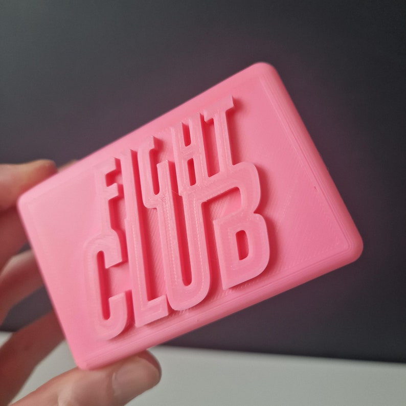 May include: A pink plastic sign with the words "FIGHT CLUB" embossed in white.