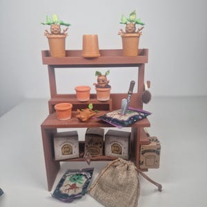 May include: A miniature brown wooden potting bench with terracotta pots, a small trowel, and seed packets. The bench features several small Mandrake figures, a plant with a human-like appearance, in various stages of growth.