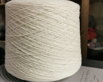 May include: A large spool of off-white yarn. The yarn is wound tightly and has a smooth texture.
