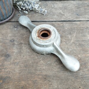 Könnte beinhalten: Ein silberner Schraubenschlüssel aus Metall mit einer runden Mitte und zwei Armen. Der Schraubenschlüssel hat ein abgenutztes, altes Aussehen mit etwas Rost auf der Oberfläche.