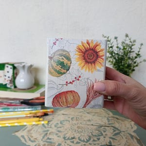 Puede incluir: Una caja de madera blanca con un dise&ntilde;o de oto&ntilde;o. La caja presenta un girasol, calabazas y bayas. La caja es perfecta para guardar objetos peque&ntilde;os o como pieza decorativa.