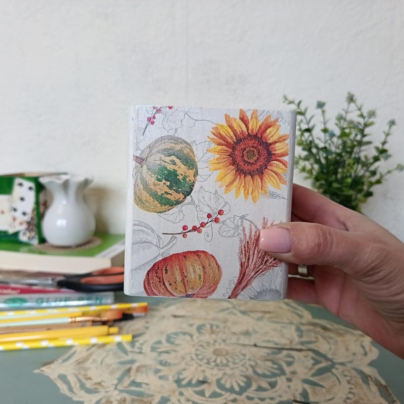 Puede incluir: Una caja de madera blanca con un dise&ntilde;o de oto&ntilde;o. La caja presenta un girasol, calabazas y bayas. La caja es perfecta para guardar objetos peque&ntilde;os o como pieza decorativa.