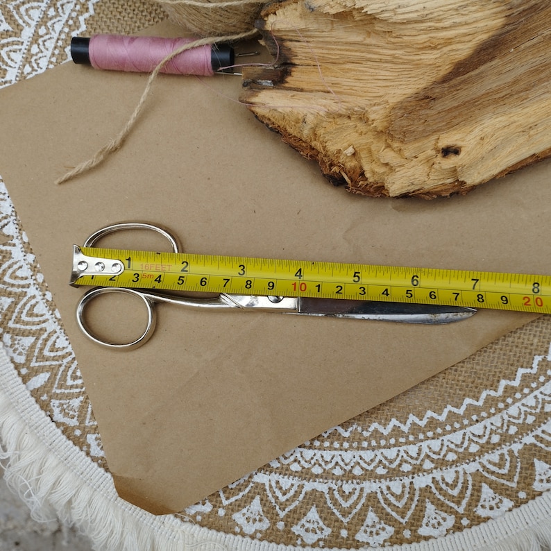 May include: A yellow measuring tape and silver scissors on a brown paper background. The tape measure reads 12 inches and 20 centimeters.