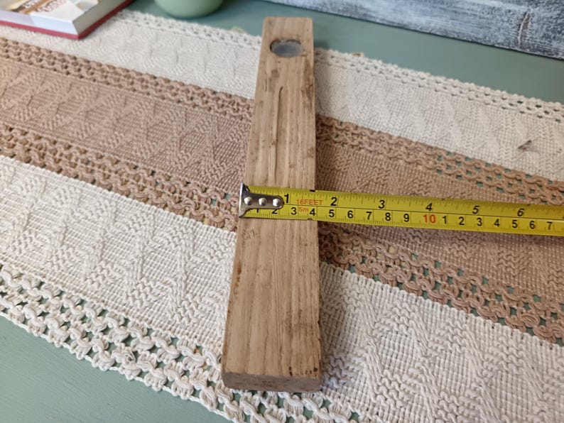 Pu&ograve; includere: Un blocco rettangolare di legno con un foro nella parte superiore, misurato con un metro a nastro per una lunghezza di circa 25 cm.