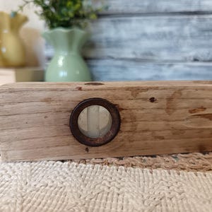Pu&ograve; includere: Un livello a bolla in legno vintage con un visore a bolla in metallo arrugginito. Il livello &egrave; in legno marrone chiaro e ha una finitura naturale.