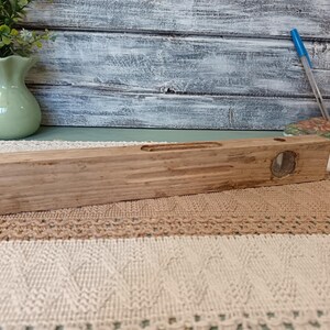 Pu&ograve; includere: Un livello in legno con una fiala a livello a bolla trasparente. Il livello &egrave; in legno naturale e ha un aspetto rustico.