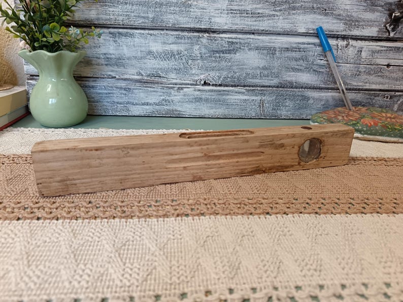 Pu&ograve; includere: Un livello in legno con una fiala a livello a bolla trasparente. Il livello &egrave; in legno naturale e ha un aspetto rustico.