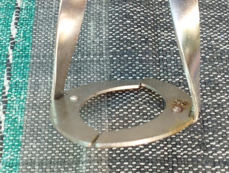 May include: A silver metal ring with a circular opening, designed to hold a coffee filter in place. The ring is made of two pieces that are joined together.