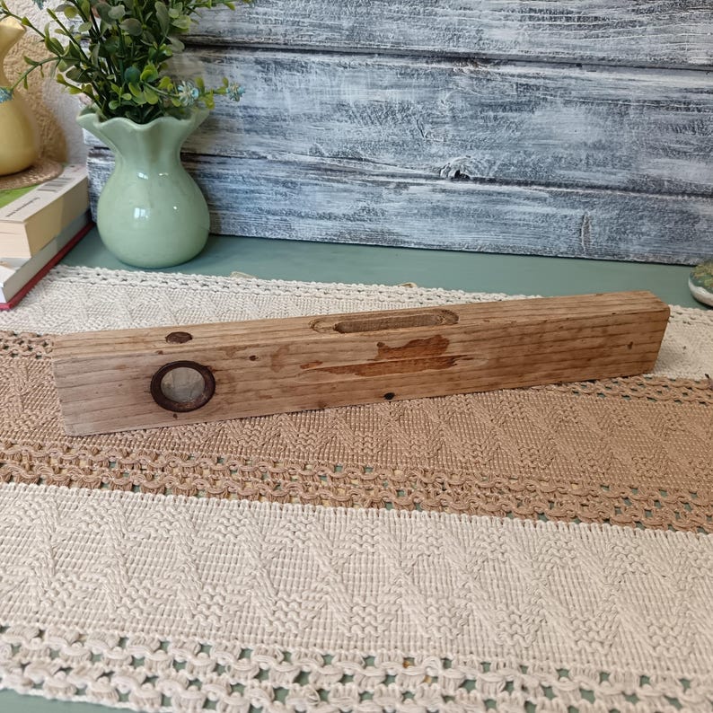 Pu&ograve; includere: Un livello in legno vintage con un livello a bolla circolare. Il livello &egrave; in legno invecchiato e ha una finitura naturale.