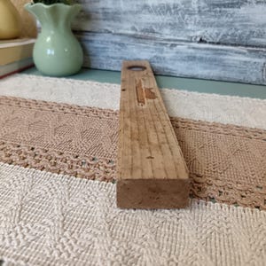 Pu&ograve; includere: Un livello in legno con un livello a bolla al centro. Il livello &egrave; in legno naturale e ha un aspetto rustico.