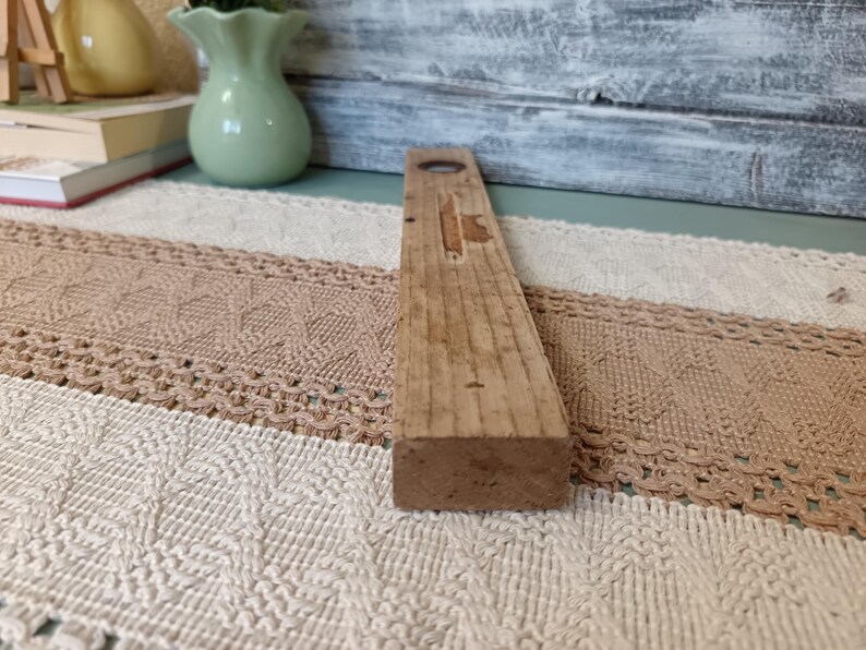 Pu&ograve; includere: Un livello in legno con un livello a bolla al centro. Il livello &egrave; in legno naturale e ha un aspetto rustico.