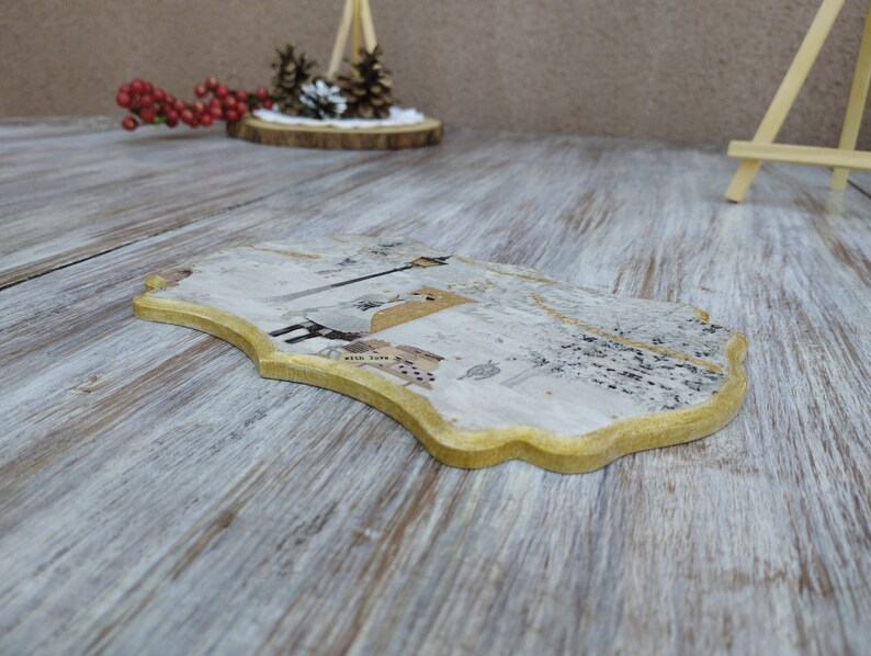 May include: A decorative wooden coaster with a gold trim and a white background. The coaster features a design of a bird with a heart and the words "with love".