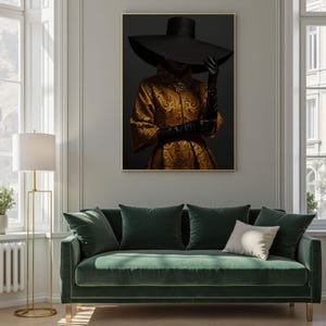 Op de afbeelding: Een ingelijste print van een vrouw die een grote zwarte hoed en een gouden, gepatroneerde jurk draagt. De vrouw staat voor een donkere achtergrond.