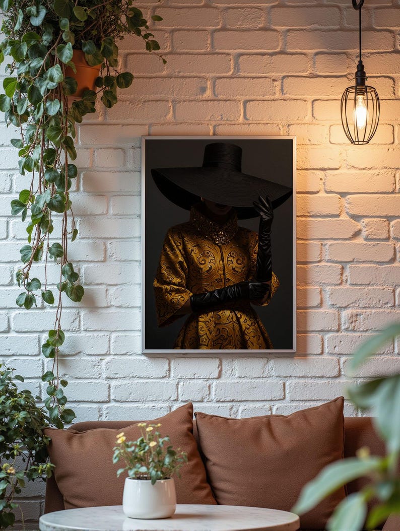 Op de afbeelding: Een ingelijste print van een vrouw die een grote zwarte hoed en een gouden geprinte jurk draagt. De vrouw staat voor een donkere achtergrond.