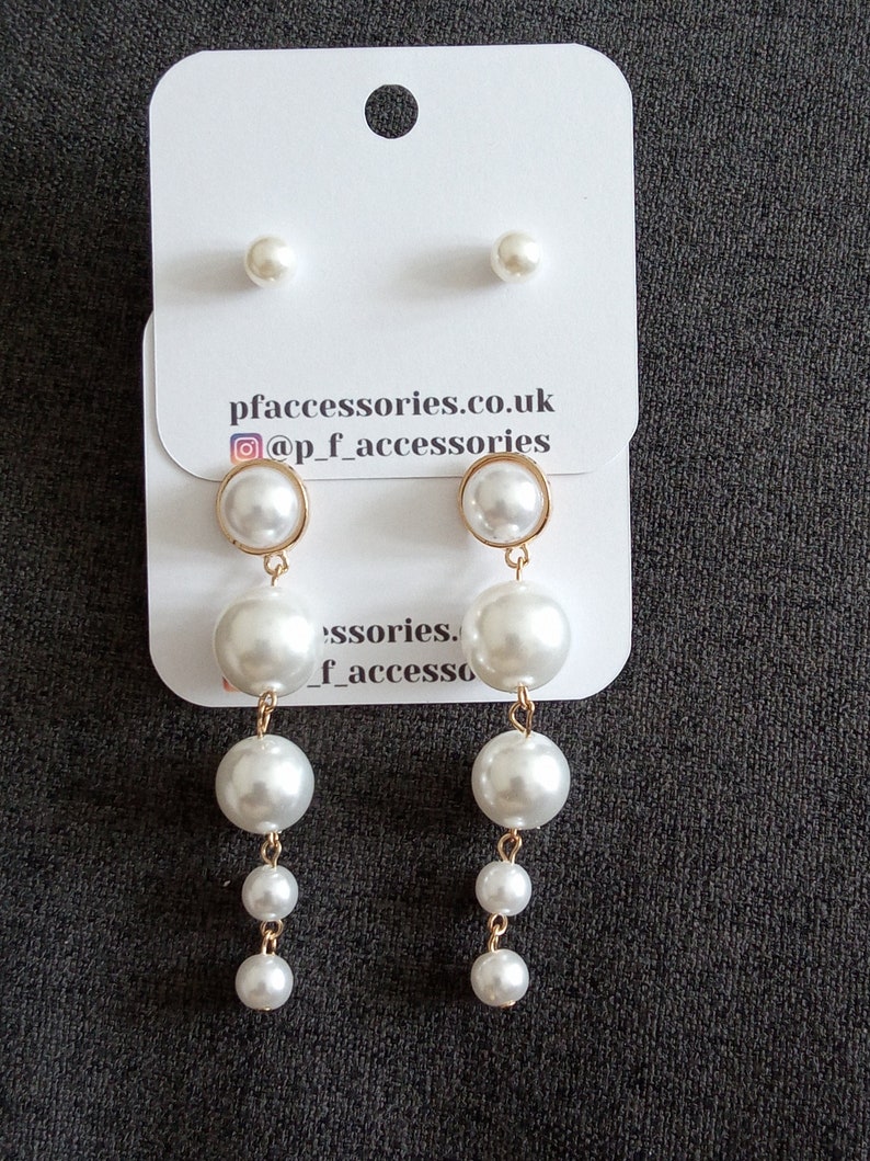 May include: A set of pearl earrings with a single pearl stud and a pair of drop earrings with three pearls each. The earrings are on a white card with the text "pfaccessories.co.uk @p_f_accessories".
