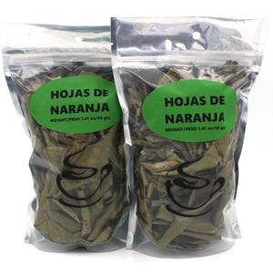 Op de afbeelding: Twee doorzichtige plastic zakken gevuld met gedroogde sinaasappelbladeren. Elke zak heeft een groen label met de tekst "HOJAS DE NARANJA" en "WEIGHT/PESO 1.41 oz/40 grs".