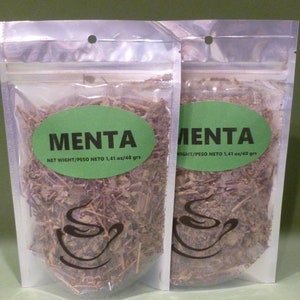 Könnte beinhalten: Zwei durchsichtige Plastiktüten mit grünen Etiketten, auf denen "MENTA" und "NET WIGHT/PESO NETO 1,41 oz/40 grs" steht. Die Tüten enthalten getrocknete Minzblätter.