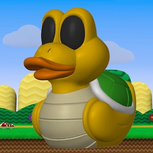 May include: A 3D rendered yellow Koopa Troopa character with a duck-like beak and black eyes. The character has a green and white shell on its back and a tan belly. The background features a blue sky, clouds, and a cartoon landscape.