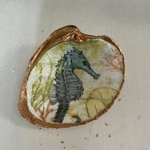 May include: A gold-rimmed seashell dish with a seahorse and seaweed design.