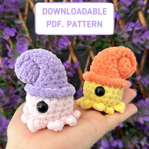 May include: Two crocheted amigurumi octopus plushies. One is pink with a purple shell and the other is yellow with an orange shell. The plushies have black eyes and are sitting on a hand. The text "DOWNLOADABLE PDF. PATTERN" is in a white box above the plushies.