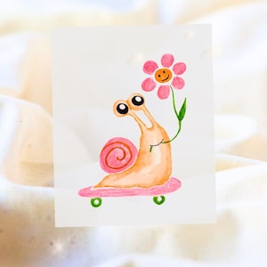 Könnte beinhalten: Aquarellillustration einer Schnecke auf einem rosa Skateboard, die eine rosa Blume mit einem lächelnden Gesicht hält. Die Schnecke hat ein rosa Gehäuse und große Augen. Das Skateboard hat grüne Räder.