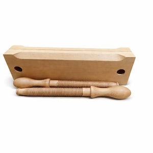 Puede incluir: Un juego de moldes de mantequilla de madera, que presenta una caja rectangular con bordes redondeados y dos moldes de madera tipo tornillo. El juego está hecho de madera de color claro y está diseñado para dar forma a la mantequilla.