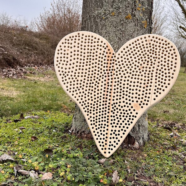 Bee hotel made of natural wood, large up to 500 holes were incorporated into a heart