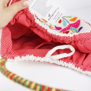 May include: Red and white polka dot fabric tote bag with a colourful embroidered design and a multi-coloured rope handle. The tag on the bag reads "Portugal Feeling".