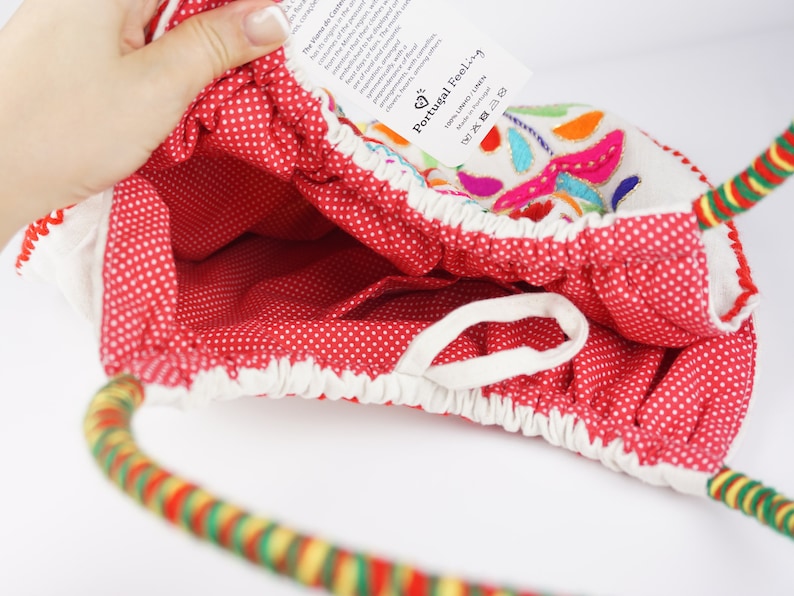 May include: Red and white polka dot fabric tote bag with a colourful embroidered design and a multi-coloured rope handle. The tag on the bag reads "Portugal Feeling".