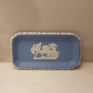 May include: A small, rectangular blue and white ceramic trinket tray with a raised white design of a mythological scene.
