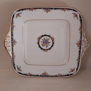 May include: A white square serving platter with a gold rim and floral design. The centre of the platter features a circular floral motif.