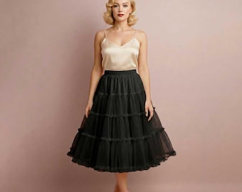 May include: A sleeveless champagne-colored camisole top with thin straps and a V-neckline paired with a black knee-length skirt featuring multiple horizontal tiers of gathered tulle fabric that create a voluminous, flared silhouette.