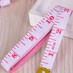 Premium Photo  Sewing background with measuring tape on pink background.  accessories of tailor or seamstress. sewing threads, needles, fabric,  sewing centimeter or measuring tape.