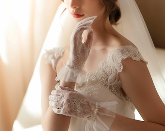 May include: A bride wearing a white lace wedding dress with a veil and white lace gloves. The gloves have a ruffled edge and are made of delicate lace.