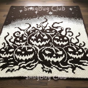 May include: A brown and white crocheted blanket with a Halloween theme. The blanket shows several jack-o'-lanterns with smiling faces. The top of the blanket has a starry night design with the text "Snugbug Club".