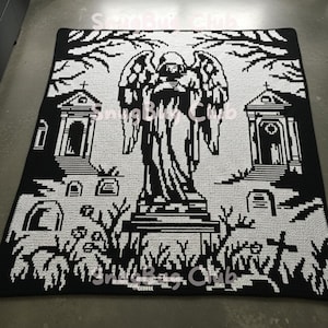 Könnte beinhalten: Schwarz-weiße Häkeldecke mit einer Friedhofsszene mit einer Engelsstatue, Grabsteinen und Bäumen. Die Decke hat ein pixeliges Design und der Text "Snug Bug Club" ist sichtbar.