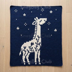 Könnte beinhalten: Eine marineblaue Häkeldecke mit einem weißen Giraffen- und Sternmuster. Die quadratische Decke besteht aus weichem, strukturiertem Material. Der Text "SnugBug Club" ist in den unteren Ecken sichtbar. Misst etwa 100 cm x 100 cm.