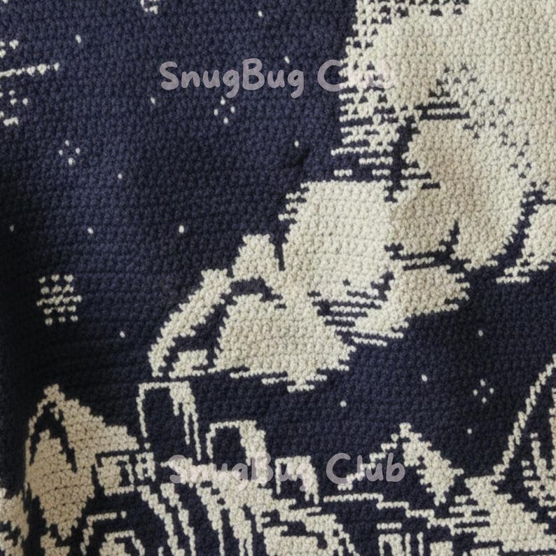 Op de afbeelding: Een marineblauwe en cr&egrave;mekleurige gehaakte deken met een winterdorpssc&egrave;ne met huizen, bomen en een sterrenhemel. De tekst "SnugBug Club" is zichtbaar. De deken is gemaakt van zacht garen.