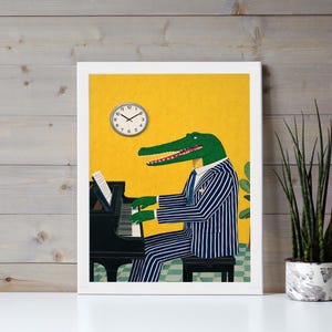May include: A framed art print featuring an alligator playing a black piano. The alligator is wearing a blue and white striped suit and tie. A clock is on the yellow wall. The print is in a white frame.