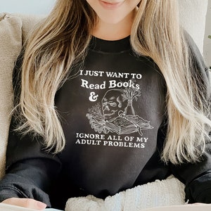 May include: A black sweatshirt with the text "I just want to read books & ignore all of my adult problems" and a skull with books and flowers.