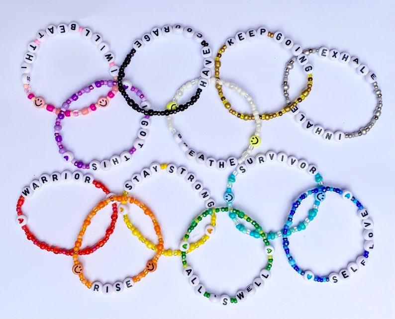 May include: A set of ten colourful beaded bracelets with positive messages, including "Warrior", "Stay Strong", "Breathe", "Rise", "All is Well", "Self Love", "Inhale Exhale", "Keep Going", "I Will Beat This", and "Got This".