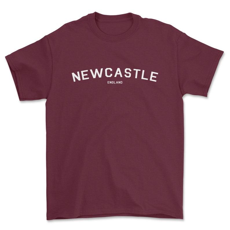 May include: Burgundy t-shirt with white text that reads "NEWCASTLE ENGLAND"