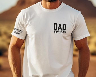 May include: White t-shirt with black text that reads "DAD EST 2025" on the front. The left sleeve has black text that reads "CUSTOM NAME".